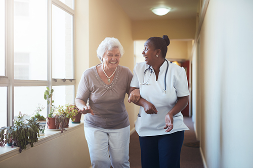 CNA walking down hallway arm and arm